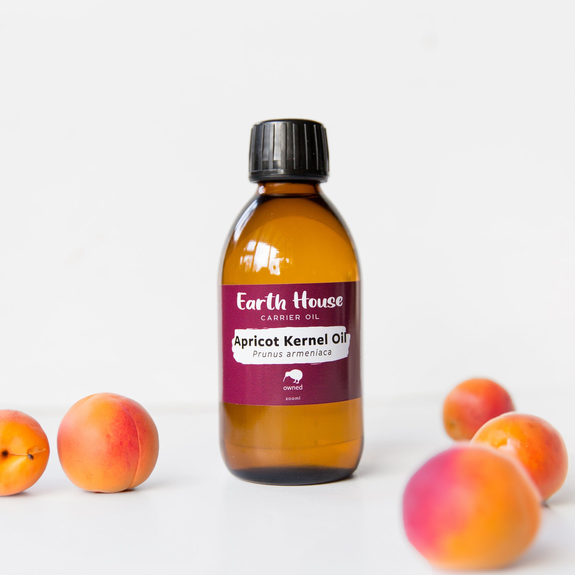 Bottle of Earth House NZ Apricot Kernel Oil, surrounding by fresh apricots