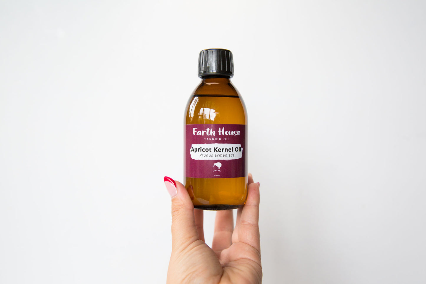 Hand holding a bottle of Earth House NZ Apricot Kernel Oil