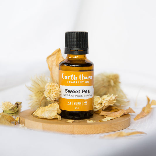 Bottle of Sweet Pea fragrant oil from Earth House on a wood dish with dried flowers and a white background